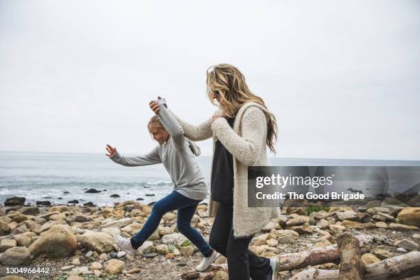 mother and young daughter enjoying walk on rocky beach - us girls on the beach stock-fotos und bilder