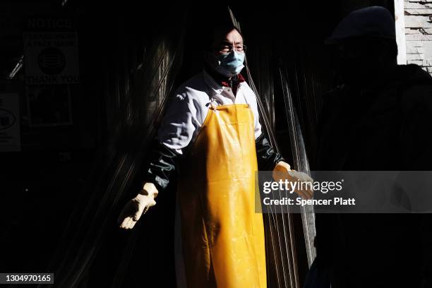 Worker pauses in front of a grocery store in the streets of Chinatown on March 02, 2021 in New York City. Chinatown, one of Manhattan's oldest...