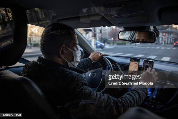 Uber driver checks his phone as he drives on February 27, 2021 in Paris, France. Despite the development of Covid-19 vaccine campaigns to prevent...