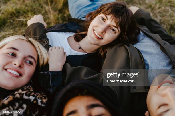 portrait of woman lying down with during sunset - menschengruppe stock-fotos und bilder