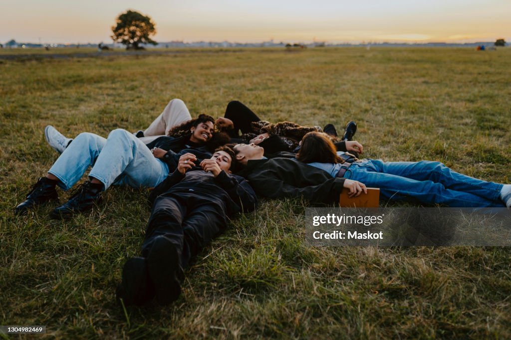 Young male and female friends lying on grass in park