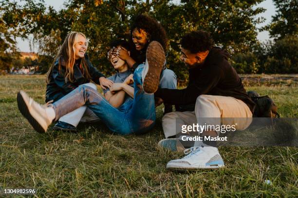 cheerful male and female friends having fun while playing in park during sunset - freundschaft stock-fotos und bilder