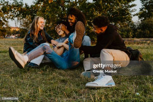 cheerful male and female friends having fun while playing in park during sunset - best friends teenagers ストックフォトと画像