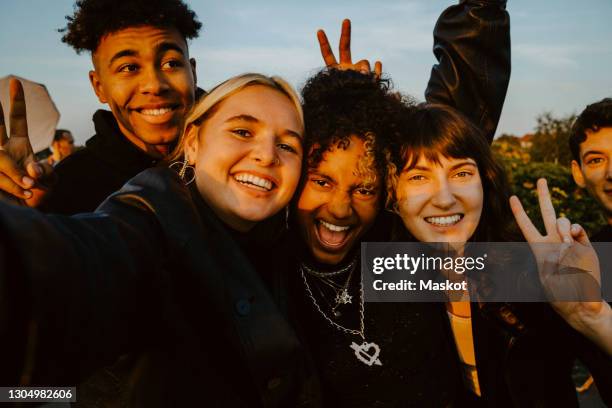 portrait of cheerful friends taking selfie outdoors during sunset - adolescents selfie ストックフォトと画像