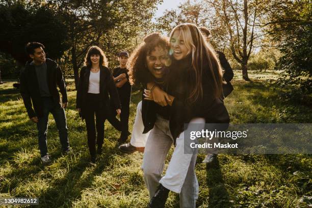 cheerful friends having fun in park - ados groupe photos et images de collection