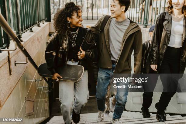 happy male and female friends climbing steps at subway - male friendship stock-fotos und bilder