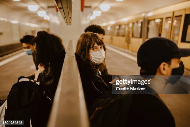 young woman with friends sitting at subway station during pandemic - epidemie stockfoto's en -beelden