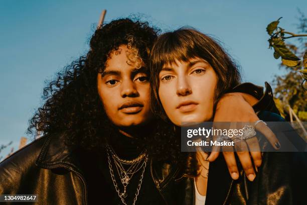 portrait of female friends with arm around outdoors on sunny day - two people hugging stock pictures, royalty-free photos & images