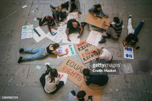 directly above of male and female protestor preparing posters for social movement - manifestante foto e immagini stock