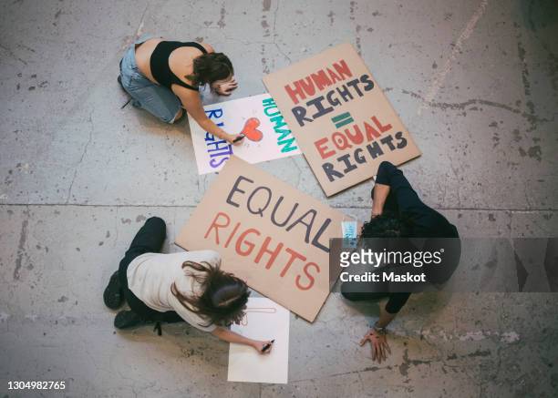 directly above of male and female activist preparing posters for social issues during pandemic - art for social justice stock-fotos und bilder