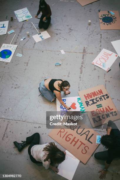 directly above of male and female protestors preparing posters for social issues during pandemic - social justice concept stock-fotos und bilder