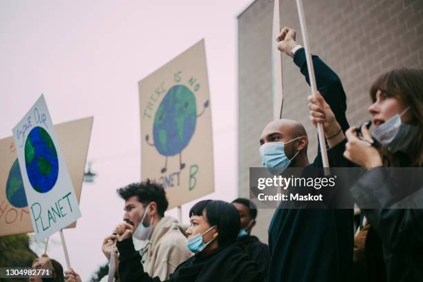 male and female activist protesting for environmental issues during pandemic - protestor mask stock-fotos und bilder