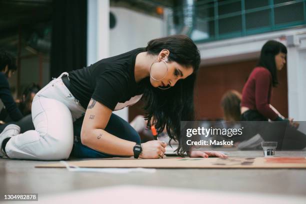 female activist preparing signboard while sitting in building to protest against social issues - teenager alter 個照片及圖片檔