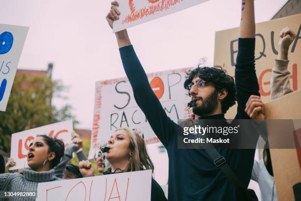 male and female activist participating in anti-racism protest - giustizia sociale foto e immagini stock