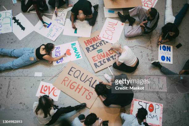 directly above of male and female activists preparing posters for social movement - activist stock pictures, royalty-free photos & images