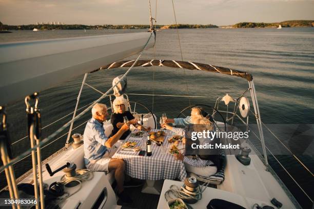 heterosexual couples toasting wineglasses while spending leisure time in sailboat - dinner on the deck stock pictures, royalty-free photos & images