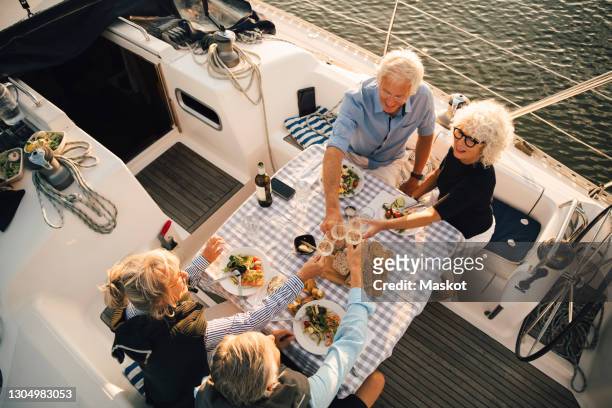 high angle view of male and female friends toasting wineglasses at table in boat - dinner on the deck stock pictures, royalty-free photos & images