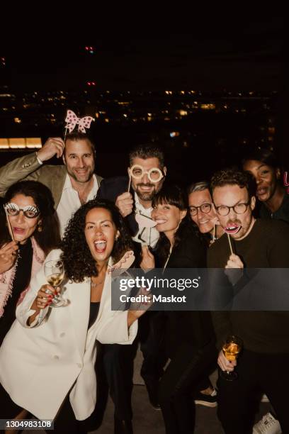 portrait of happy business people with props in office at night - work party - fotografias e filmes do acervo