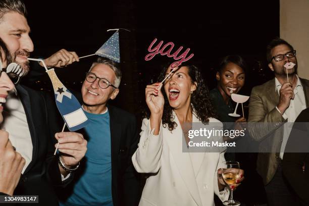 cheerful business people enjoying with props during company party at night - office party stockfoto's en -beelden