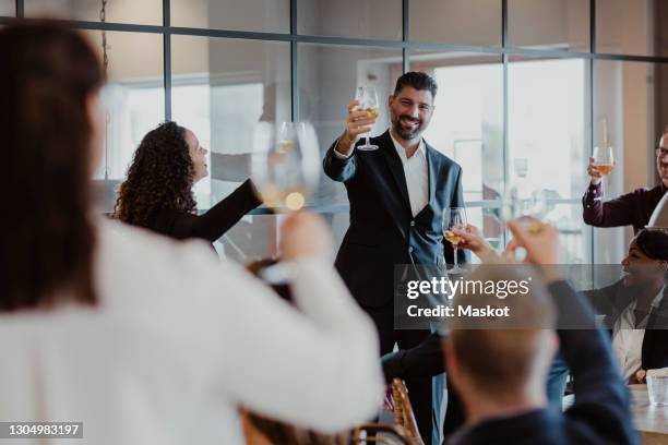 cheerful male and female toasting wineglasses during office party - office party stock pictures, royalty-free photos & images