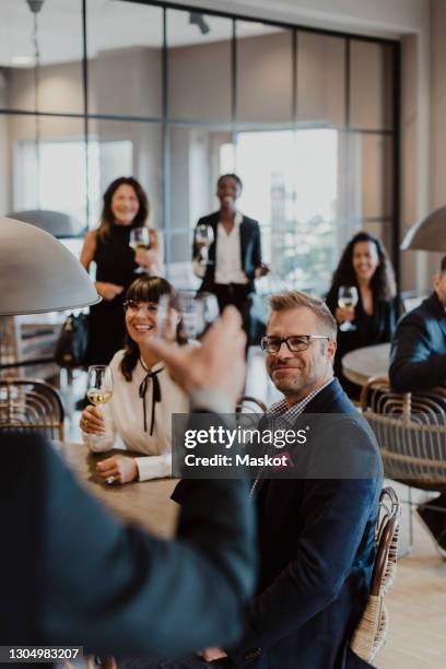 smiling male and female toasting wineglasses in party at office - equipment launch party foto e immagini stock