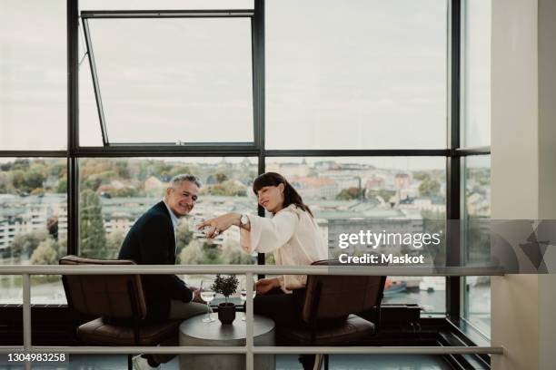 smiling male and female colleagues taking selfie on smart phone at office - anstoß sportbegriff stock-fotos und bilder