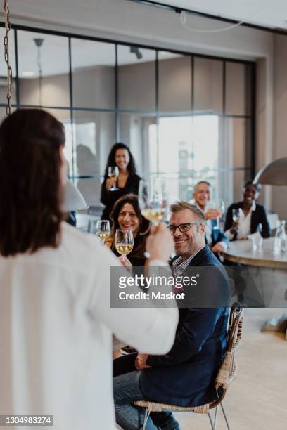 female entrepreneur with wineglass looking at colleagues during company party - 2020 kick off stock pictures, royalty-free photos & images