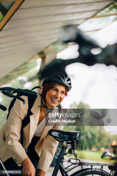 female student laughing while standing by bicycle in college campus - bicycle parking station stock pictures, royalty-free photos & images