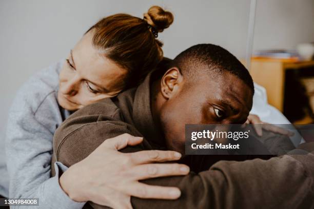 mother consoling depressed son at home - emotional stress stockfoto's en -beelden