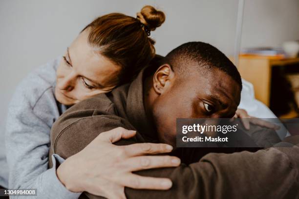 mother consoling depressed son at home - mental illness stock pictures, royalty-free photos & images