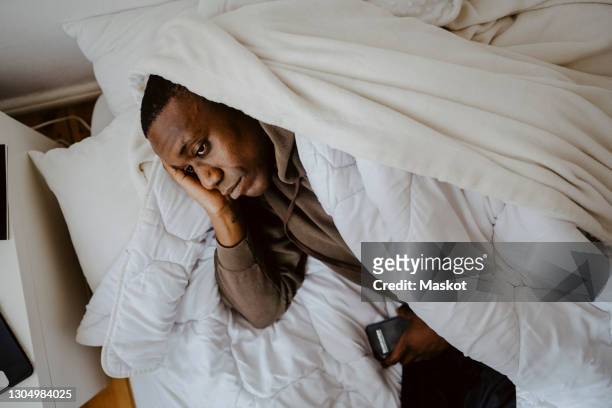 high angle view of exhausted man lying on bed at home - anxiety man stock pictures, royalty-free photos & images