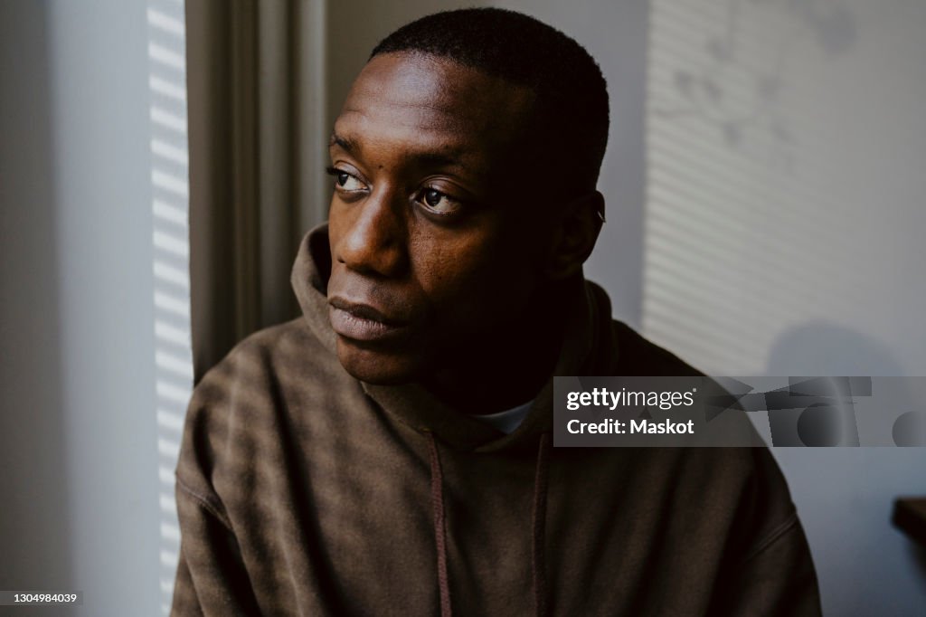 Thoughtful man looking away against wall
