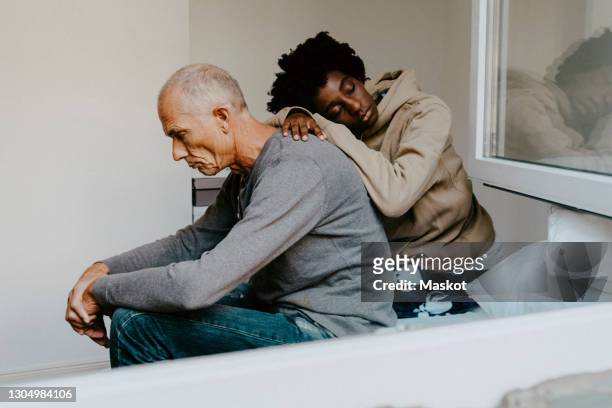 stressed father and daughter sitting in bedroom - senior im bett stock-fotos und bilder