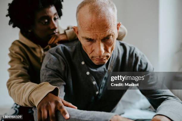 daughter consoling depressed father at home - mental illness stock-fotos und bilder