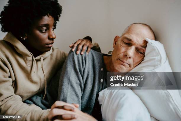daughter consoling worried father at home - old man young woman stockfoto's en -beelden