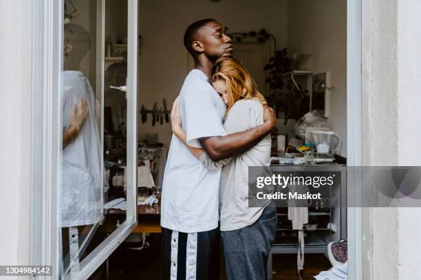son consoling depressed mother seen through window at home - menselijke relaties stockfoto's en -beelden