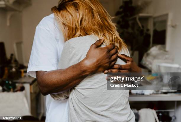 son embracing mother in living room - sadness stock-fotos und bilder
