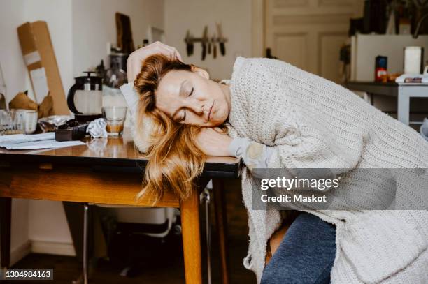 mature woman with eyes closed on table in living room - exhaustion 個照片及圖片檔