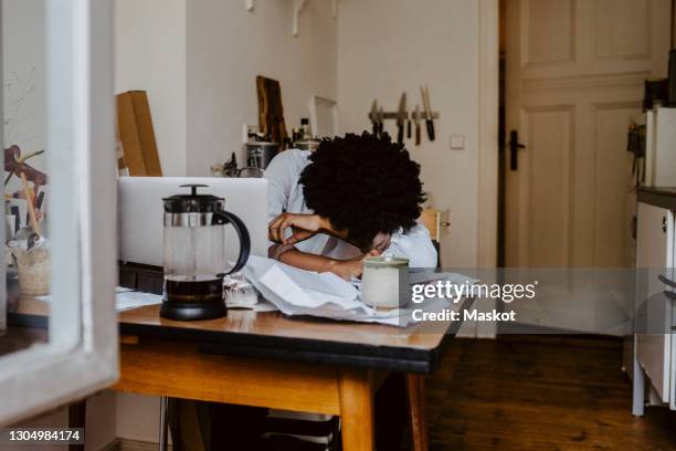 young businesswoman with head down on table in living room - head on table stock-fotos und bilder