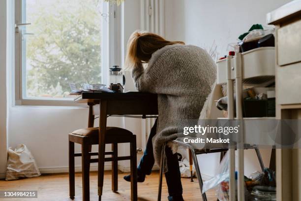 rear view of woman sitting on chair at home - overstuur stockfoto's en -beelden