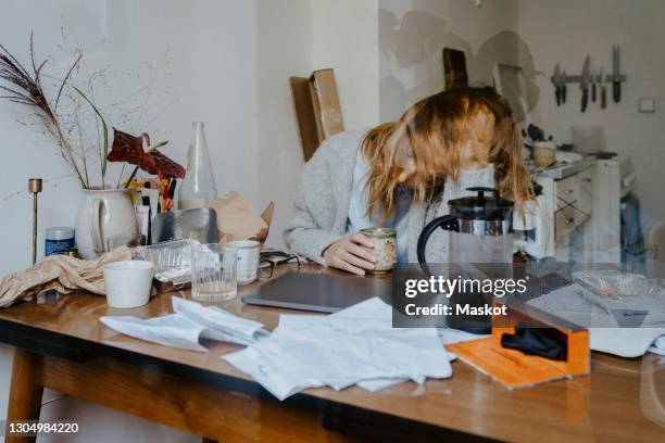emotionally stressed businesswoman with coffee cup at table in living room - overworked computer stock pictures, royalty-free photos & images