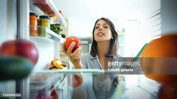frau holt einige früchte und gemüse aus dem kühlschrank. - refrigerator stock-fotos und bilder