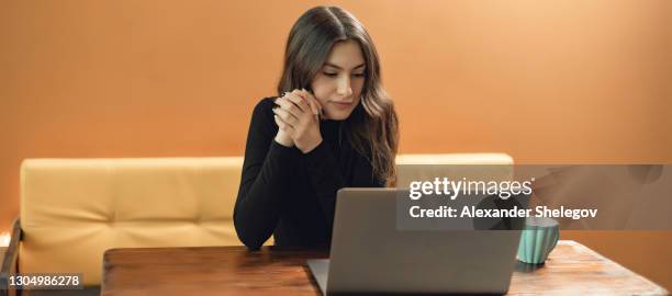 コピースペースを持つ黄色の背景に若い女の子の肖像画。ホット飲料とグレーのラップトップとのコンセプト。彼女はコーヒーを飲んで、コンピュータで働いています - arab woman fashion ストックフォトと画像