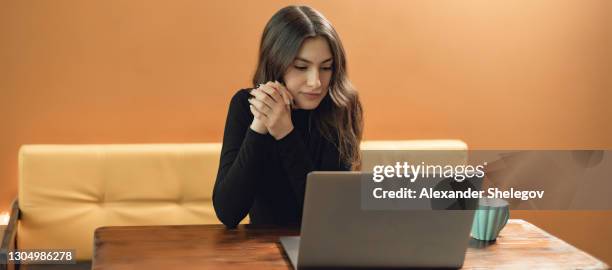 portret van jong meisje op gele achtergrond met exemplaarruimte. concept met hete drank en grijze laptop. ze drinkt koffie en werkt aan de computer. - cute arab girls stockfoto's en -beelden