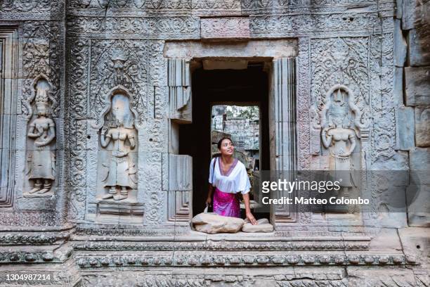woman looking out of a window in a temple, angkor, cambodia - cambodia fotografías e imágenes de stock