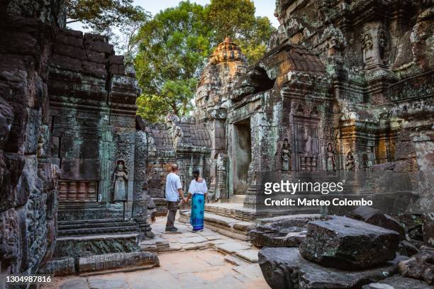adult couple visiting the temple ruins of angkor, cambodia - angkor wat photos et images de collection