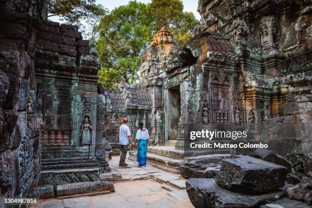 adult couple visiting the temple ruins of angkor, cambodia - angkor wat foto e immagini stock