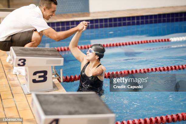 portrait of one armed female swimming athlete celebrating with her coach - swimming coach stock pictures, royalty-free photos & images