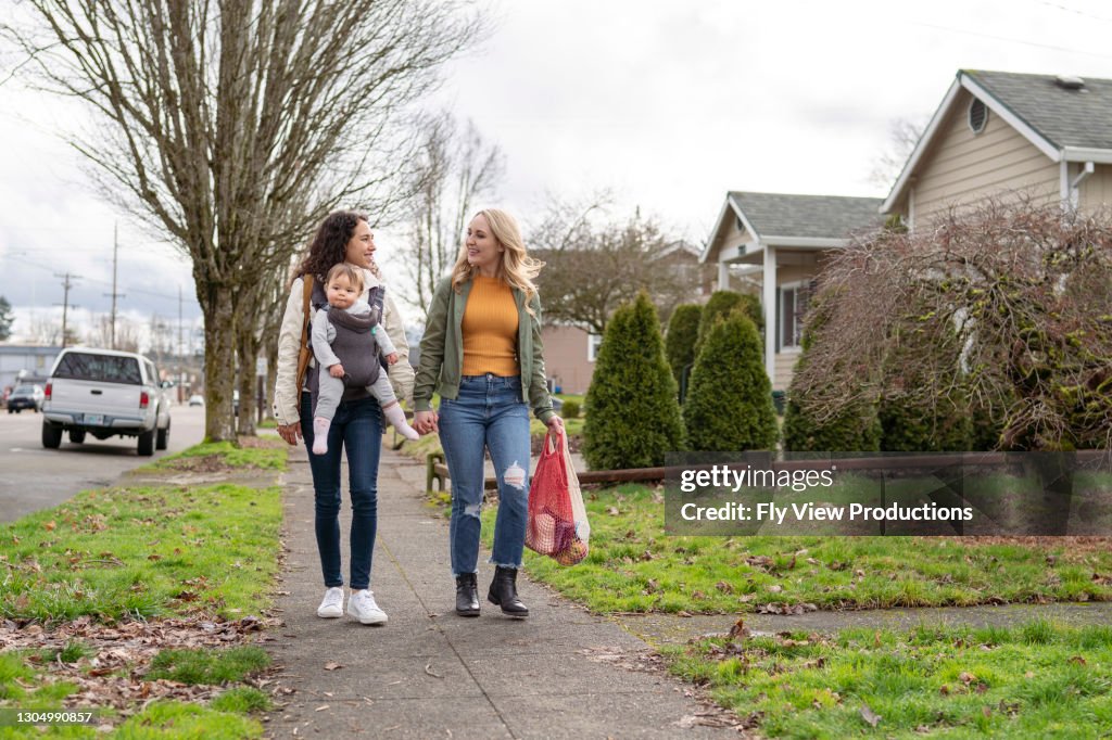 Lyckligt lesbiskt par som lever hållbar livsstil går med baby efter matinköp