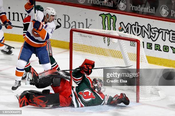 Aaron Dell of the New Jersey Devils makes a save as Cal Clutterbuck of the New York Islanders stands by in the third period at Prudential Center on...